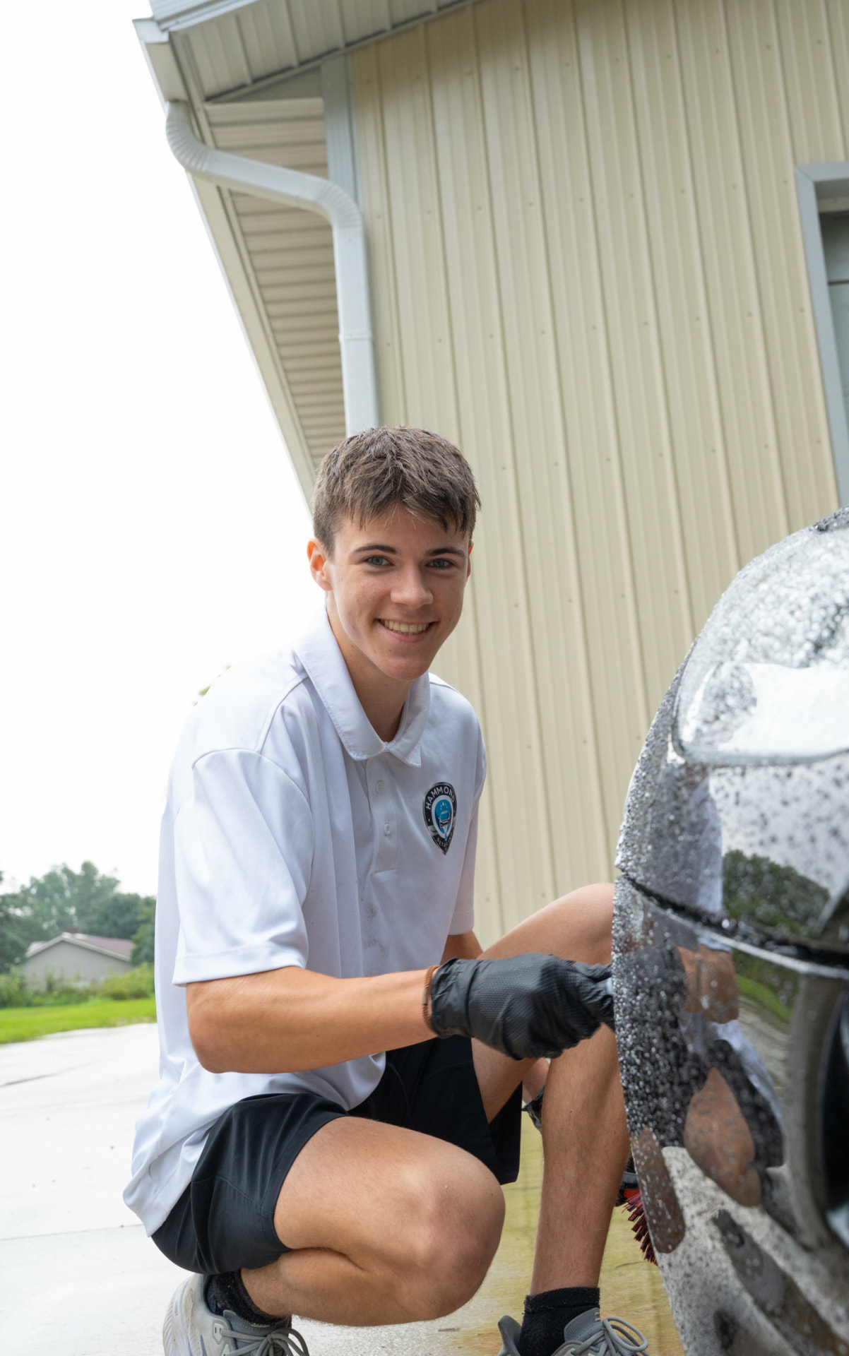Technician scrubbing a wet black car panel