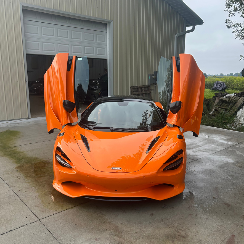 Orange McLaren 750S with dihedral doors open after a detail