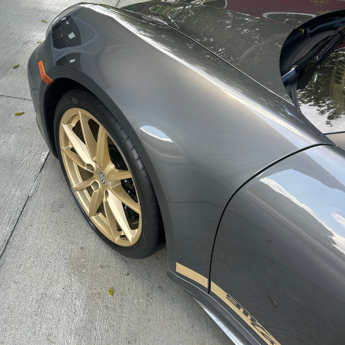 Close-up of a grey Porsche 911 GT3 fender and gold wheel