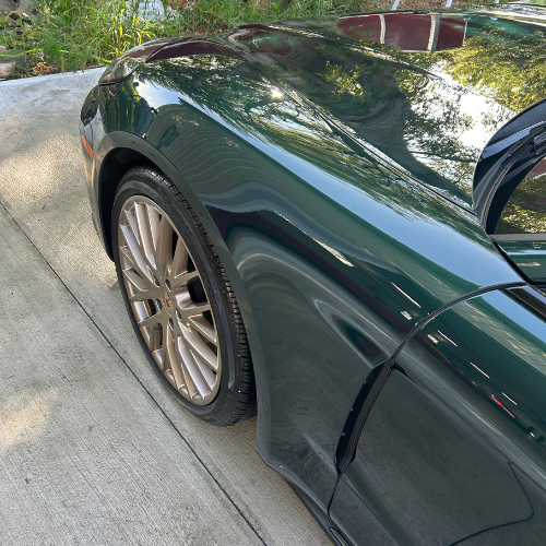 Close-up of a green Porsche fender and gold wheel after polishing
